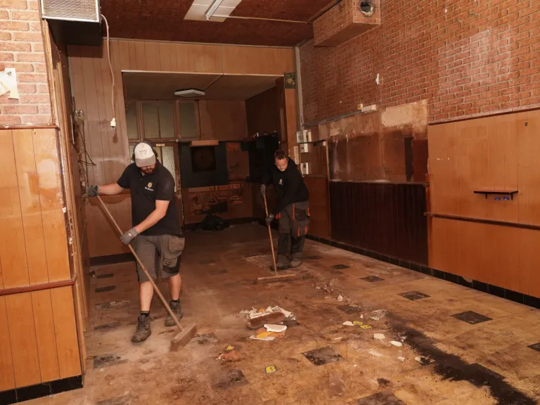 twee werknemers met borstel lege ruimte aan het schoonmaken